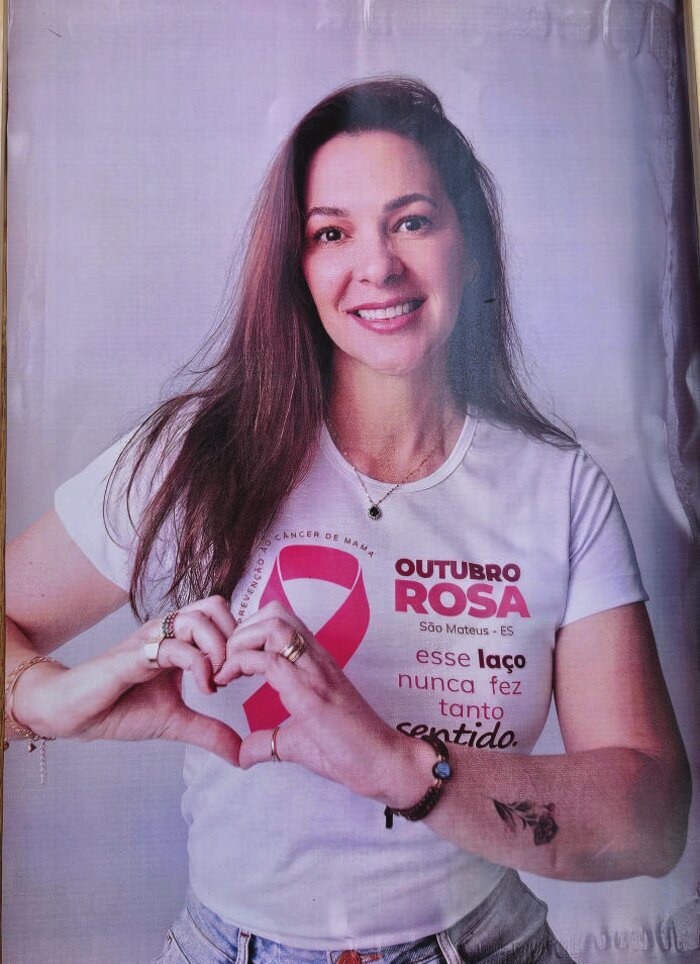 Voluntária do Outubro Rosa fazendo o gesto de coração com as mãos